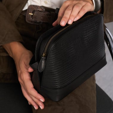 Mittlere Ledertasche in Lederfarbe, Frontalansicht, geneigt, auf einer Vase ruhend - MONPIEL 2