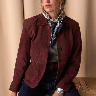 Veste en cuir camel avec détails de coutures, posée sur les épaules, vue de profil, plan large du modèle assis sur une - MONPIEL 2