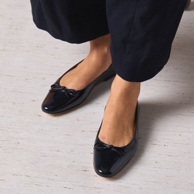 Manolita pointed-toe ballerina in black with perspective view, resting on a stone in close-up - MONPIEL 2