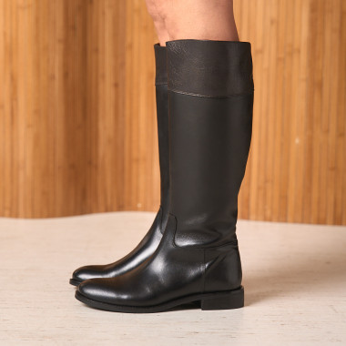 Hohe flache Stiefel in Schwarz, Seitenansicht in Nahaufnahme mit zusammenstehenden Füßen auf dem Boden – MONPIEL