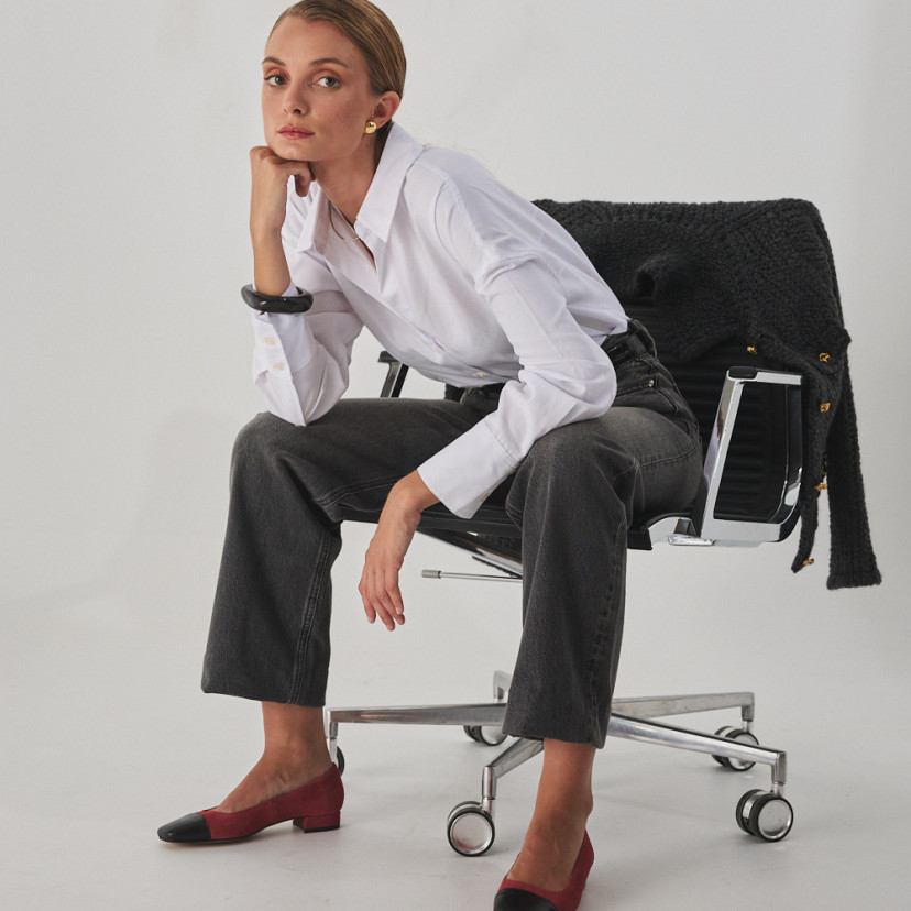 Zapato de mujer punta cuadrada de piel en color rosa ante con puntera negra, modelo sentada en la silla plano general - MONPIEL