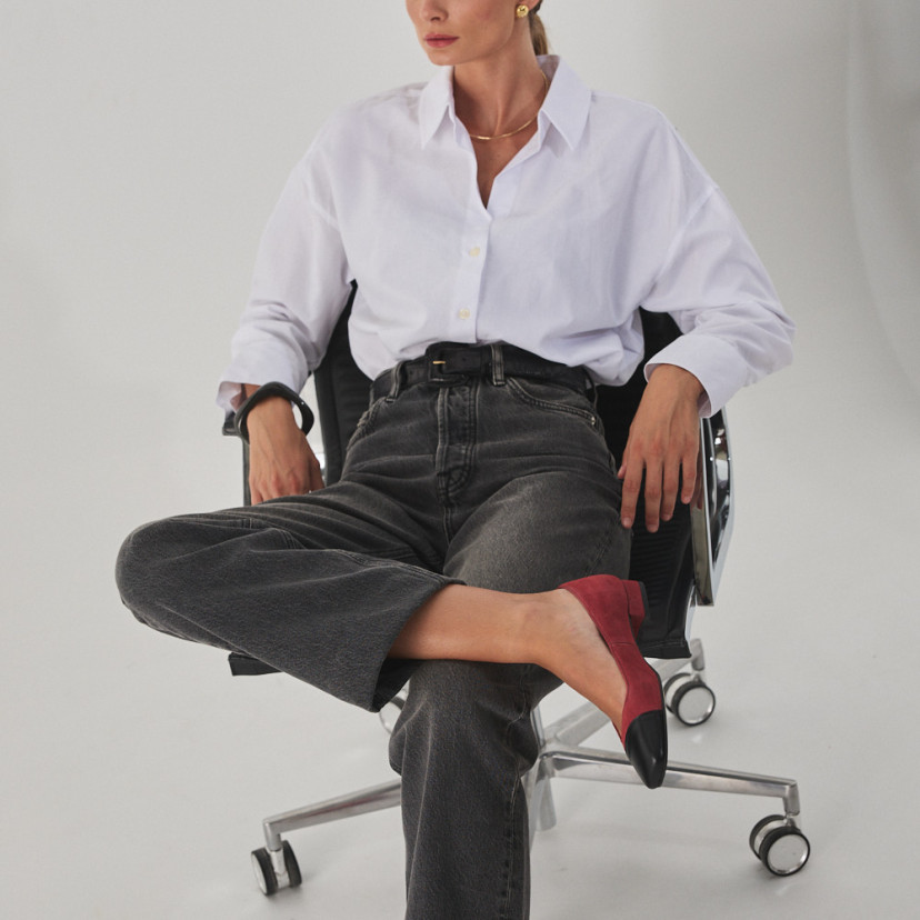 Sapato feminino com ponta quadrada de couro em rosa camurça e bico preto, modelo sentada na cadeira com perna cruzada - MONPIEL