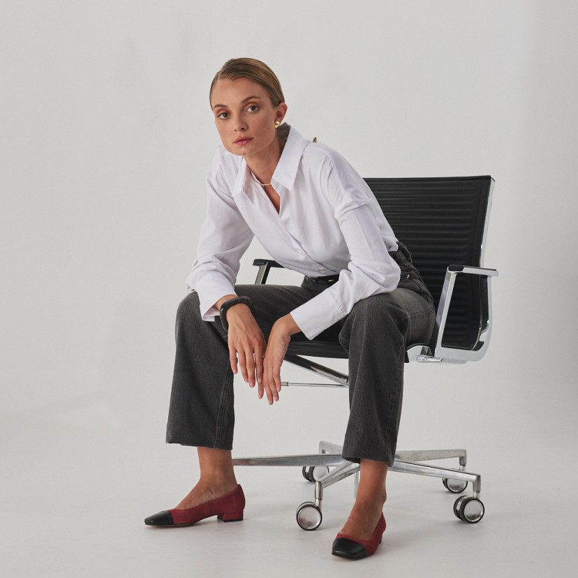 Chaussure pour femme à bout carré en cuir rose daim et bout noir, modèle assis sur la chaise, plan général - MONPIEL