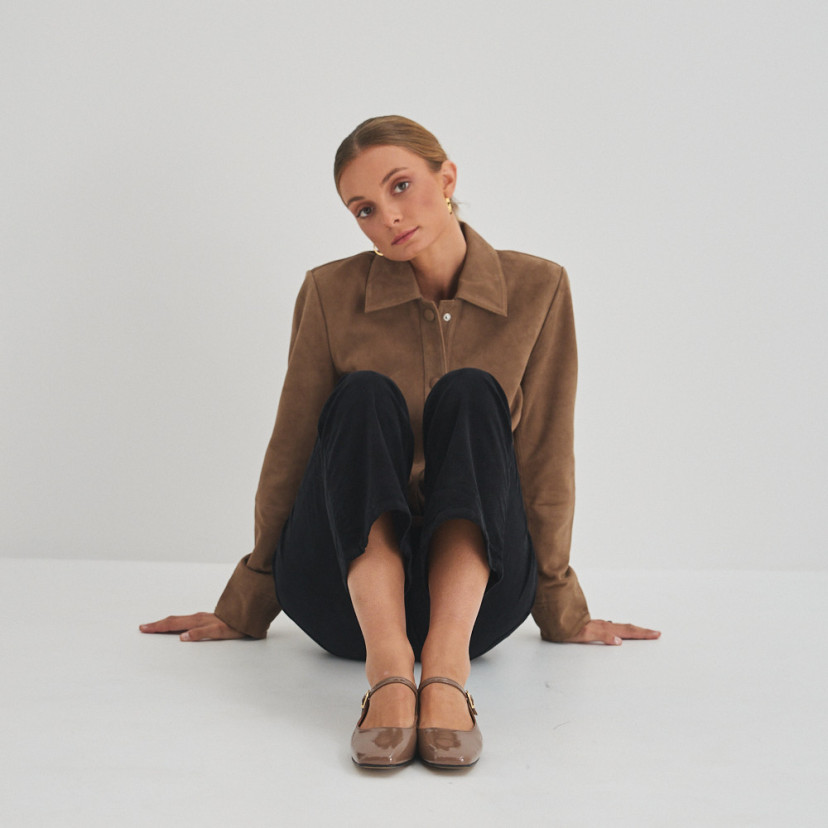 Cinnamon patent leather strap Mary Jane Carlota, front view, wide shot of model sitting on the floor - MONPIEL