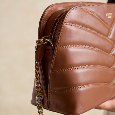 Sac matelassé en cuir couleur cuir avec chaîne dorée, à côté de savons - MONPIEL 2