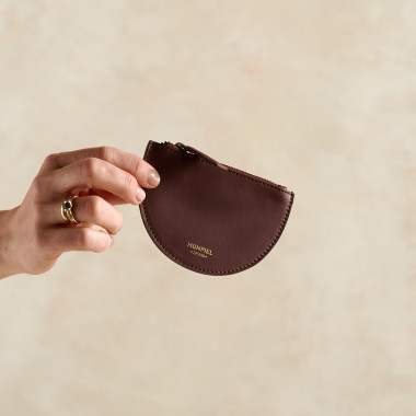 Portefeuille en cuir en forme de demi-lune couleur cuir tenu dans les mains avec fond extérieur - MONPIEL 2