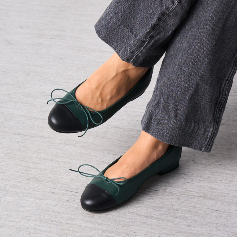 Ballerina piatta in pelle color verde con punta nera, primo piano con piedi incrociati - MONPIEL