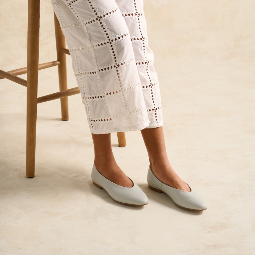 Ballerina Shoe Flat Amelié in mint green color seated on a stool in a high-angle shot - MONPIEL